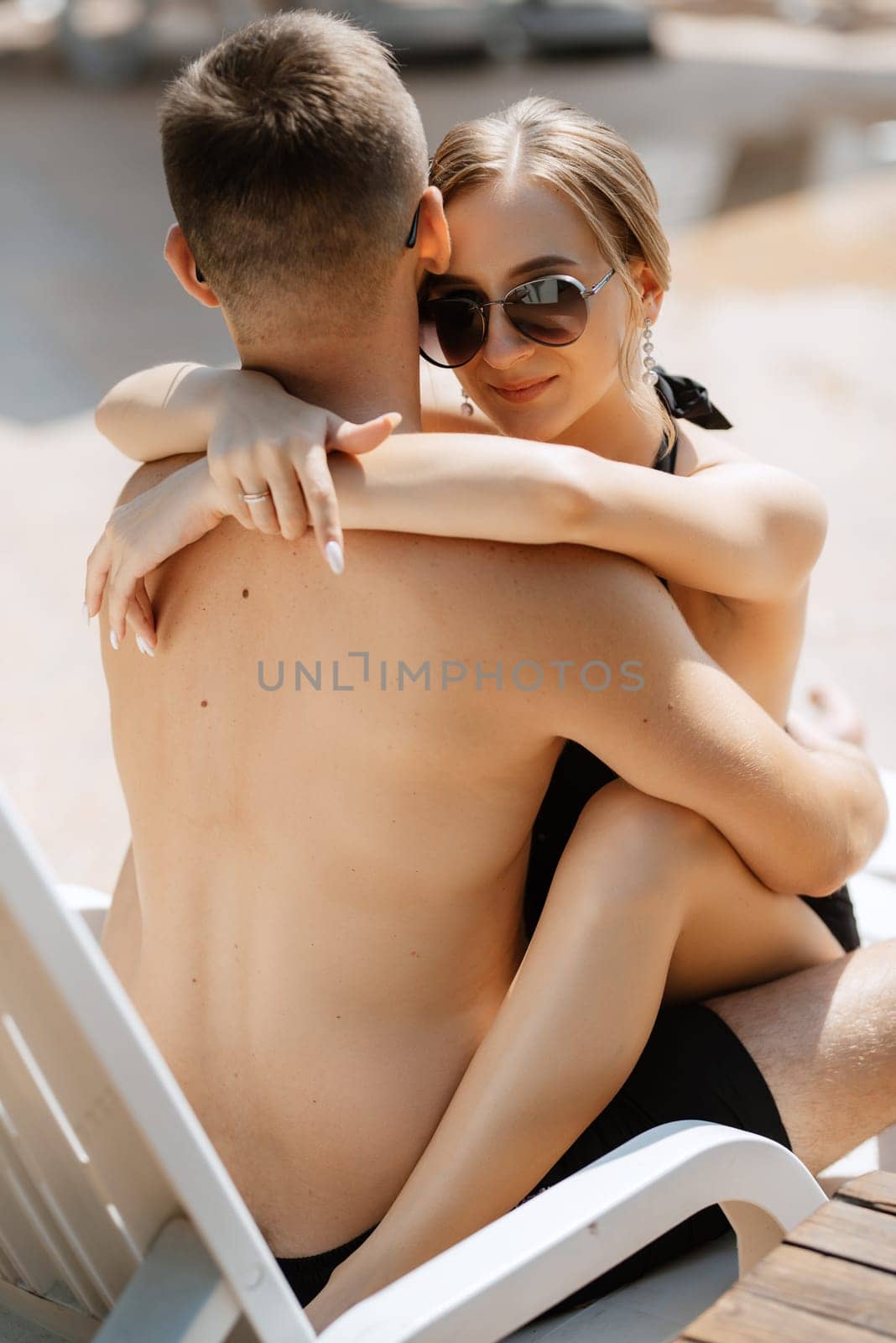 guy and a girl in bathing suits are relaxing, near the blue pool by Andreua