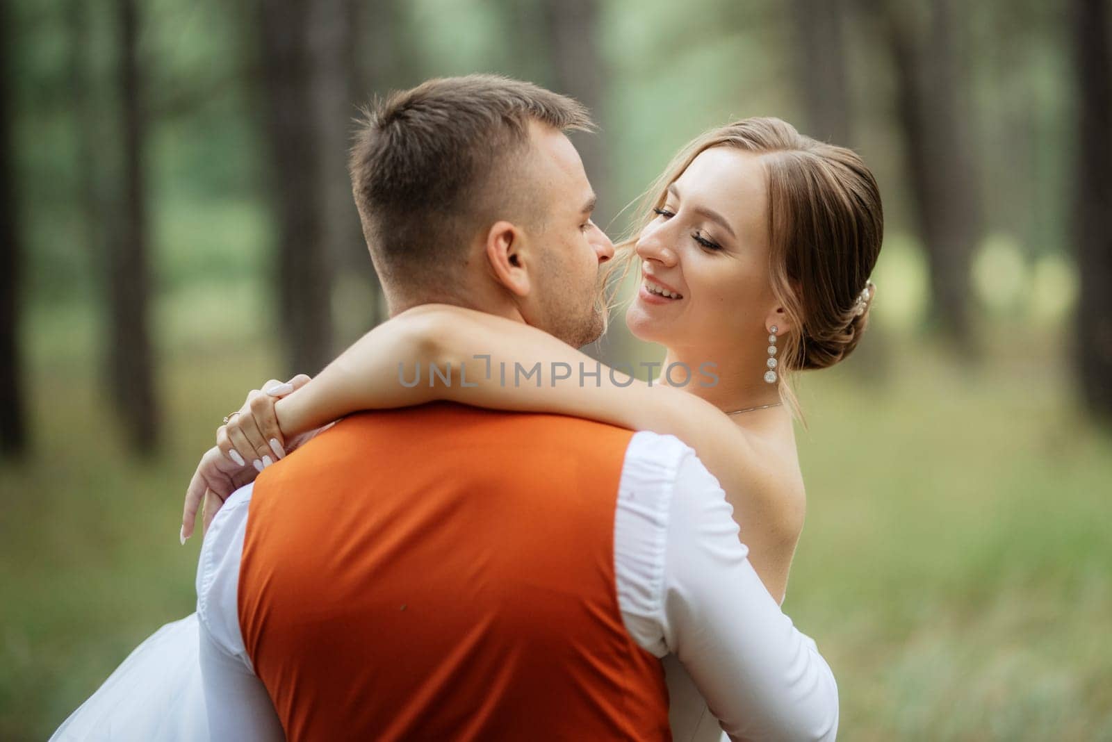 young couple bride in a white short dress and groom in a gray suit in a pine forest by Andreua