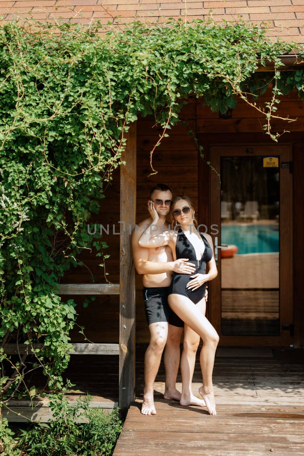 guy and a girl in bathing suits are relaxing, near the blue pool by Andreua