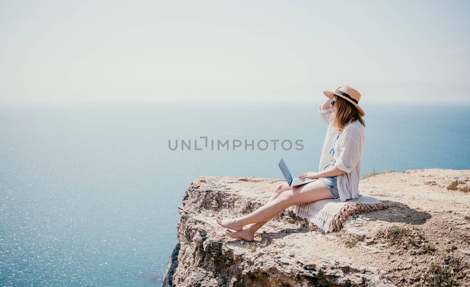 Woman sea laptop. Successful business woman working on laptop by the sea. Pretty lady typing on computer at summer day outdoors. Freelance, digital nomad, travel and holidays concept. by panophotograph