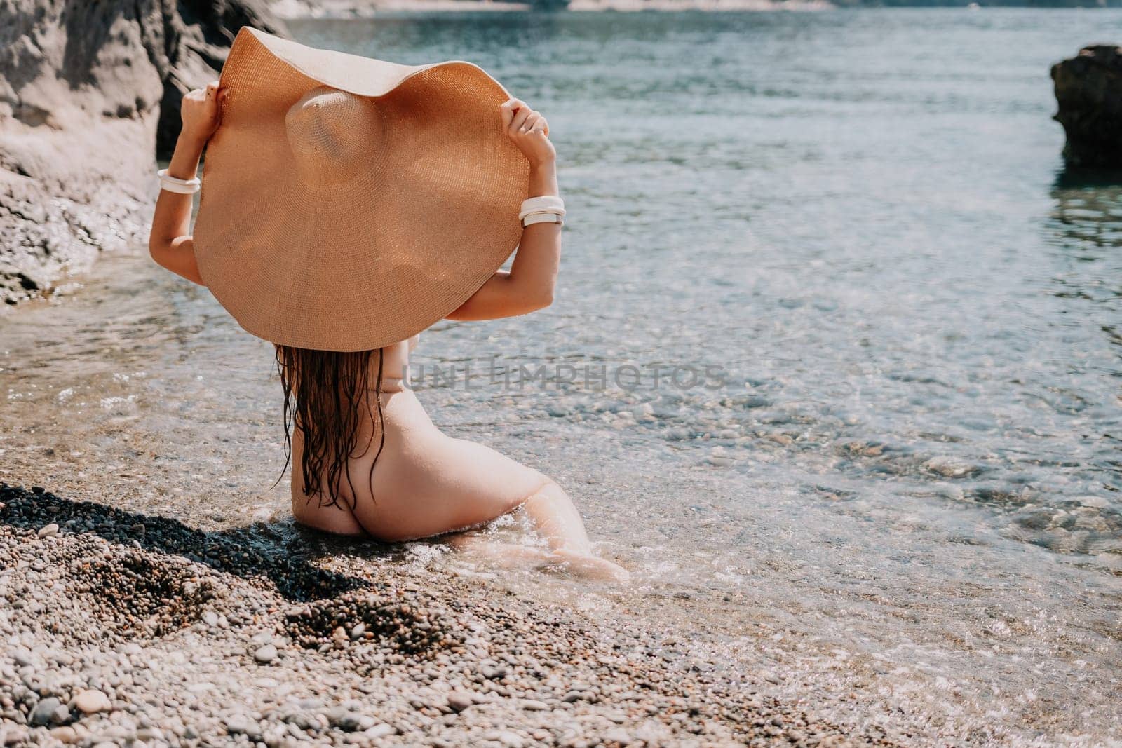 Woman travel sea. Happy tourist in hat enjoy taking picture outdoors for memories. Woman traveler posing on the beach at sea surrounded by volcanic mountains, sharing travel adventure journey by panophotograph