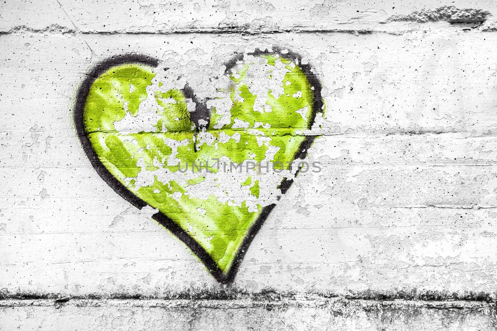 Painted lime green abstract heart shape love symbol, dirty wall background, metaphor to urban and romantic valentine, grunge style.