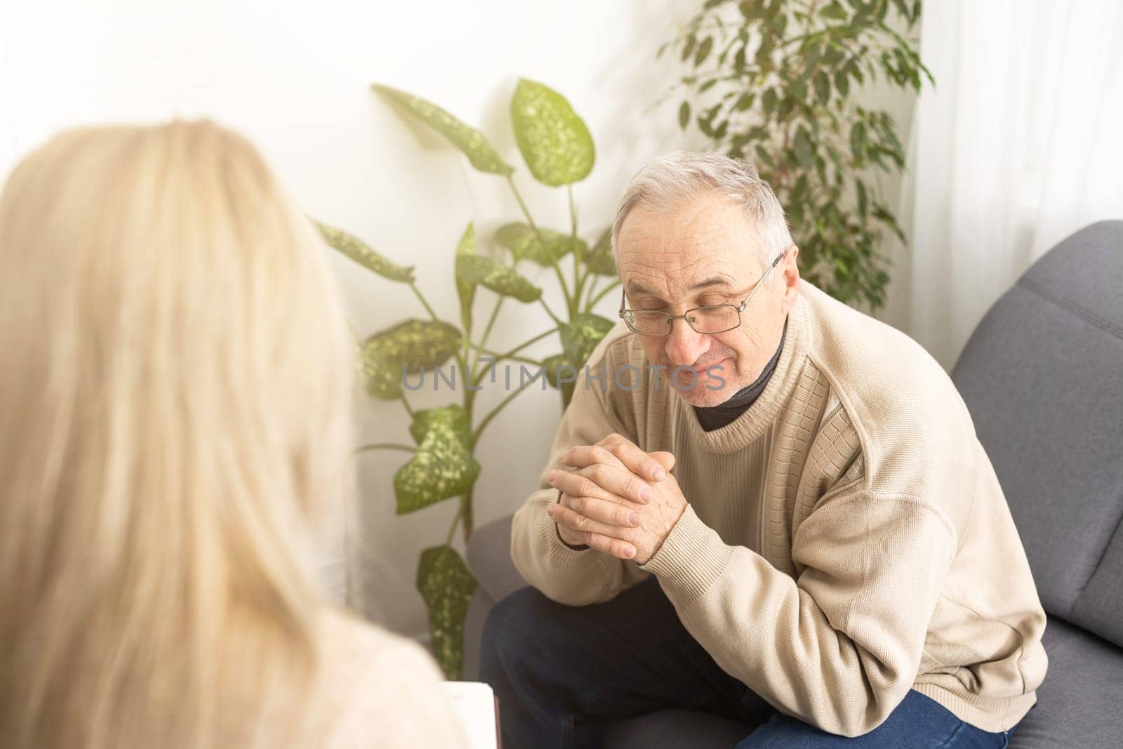 Senior man patient and young woman caregiver medical worker in uniform hold clipboard noting personal information talking listens client telling about health complaints, care support nursing concept