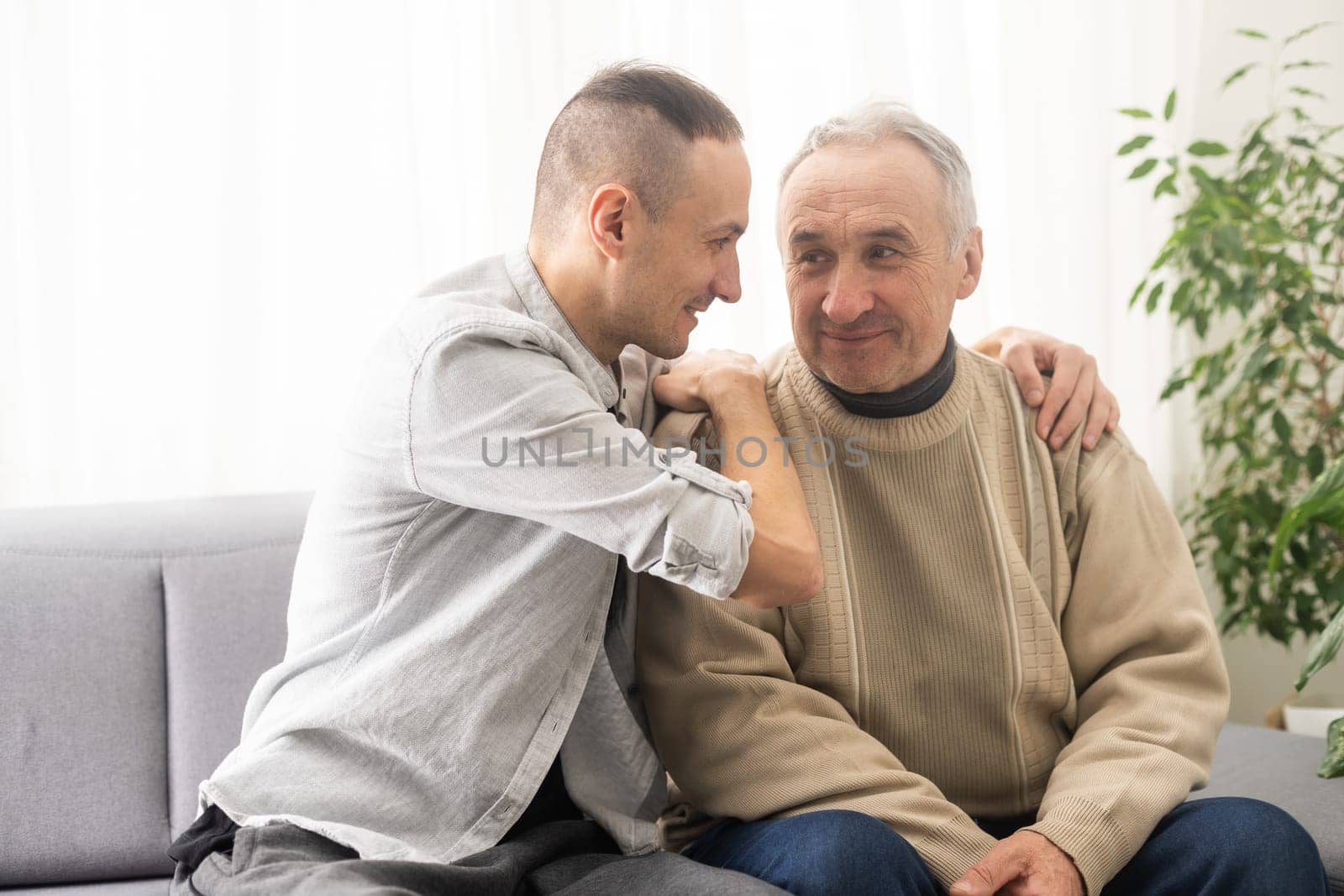 Help needed. Pleasant senior man sitting on the sofa.