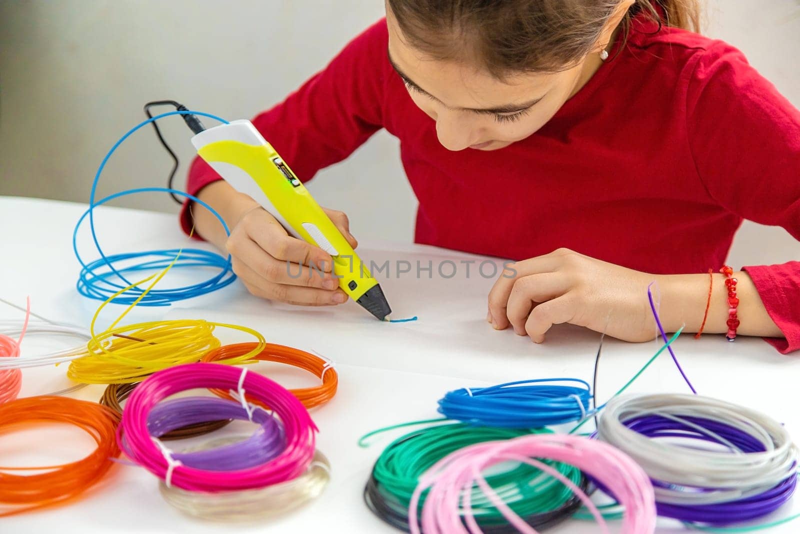 Child 3D drawings with a pen on the table. Selective focus. Kid.