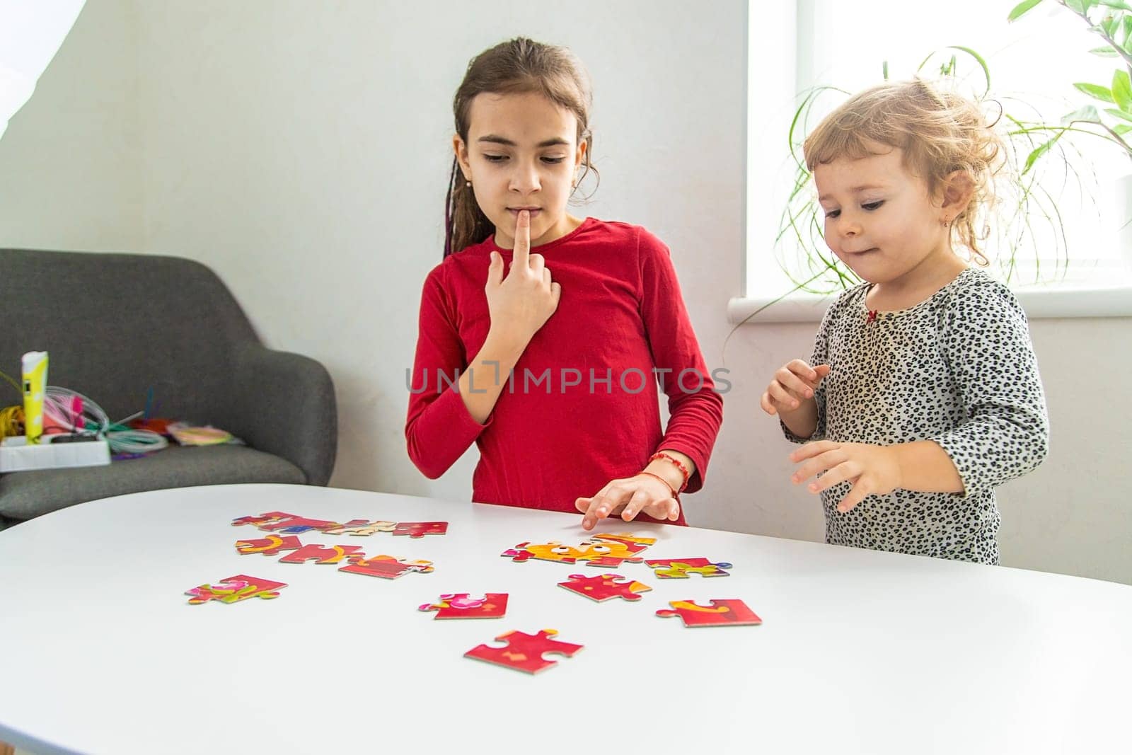 Children put together a puzzle on the table. Selective focus. Kid.