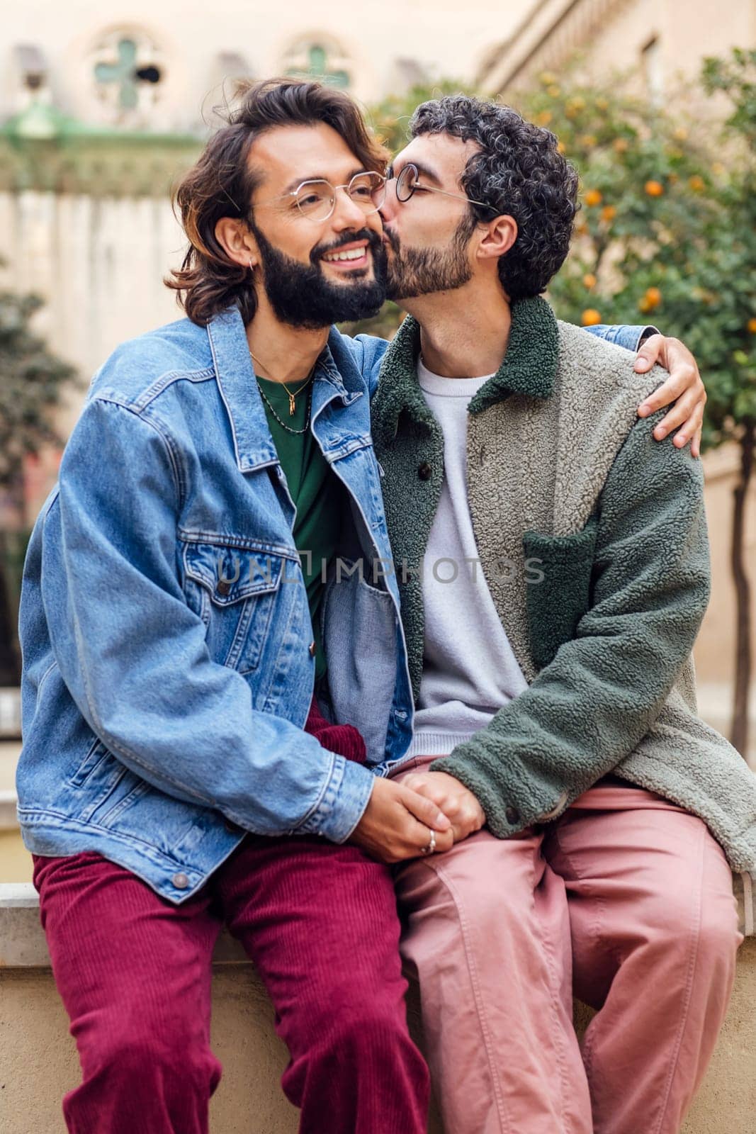 young man kissing tenderly his boyfriend's cheek, concept of urban lifestyle and love between people of the same sex
