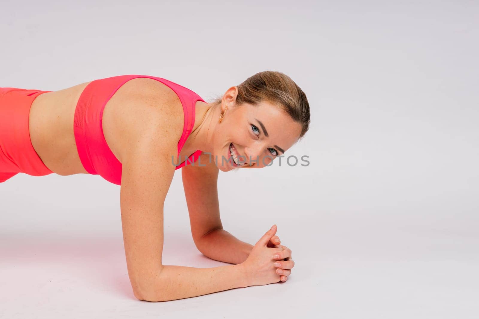 Beautiful female with dumbbells posing on a studio background