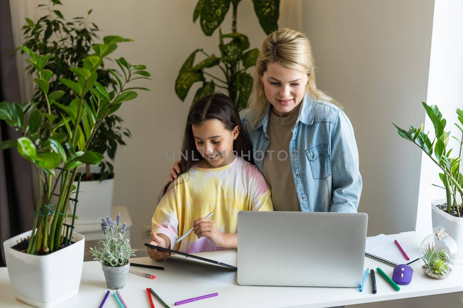 Back to school. Happy child and adult are sitting at desk. Girl doing homework or online education.