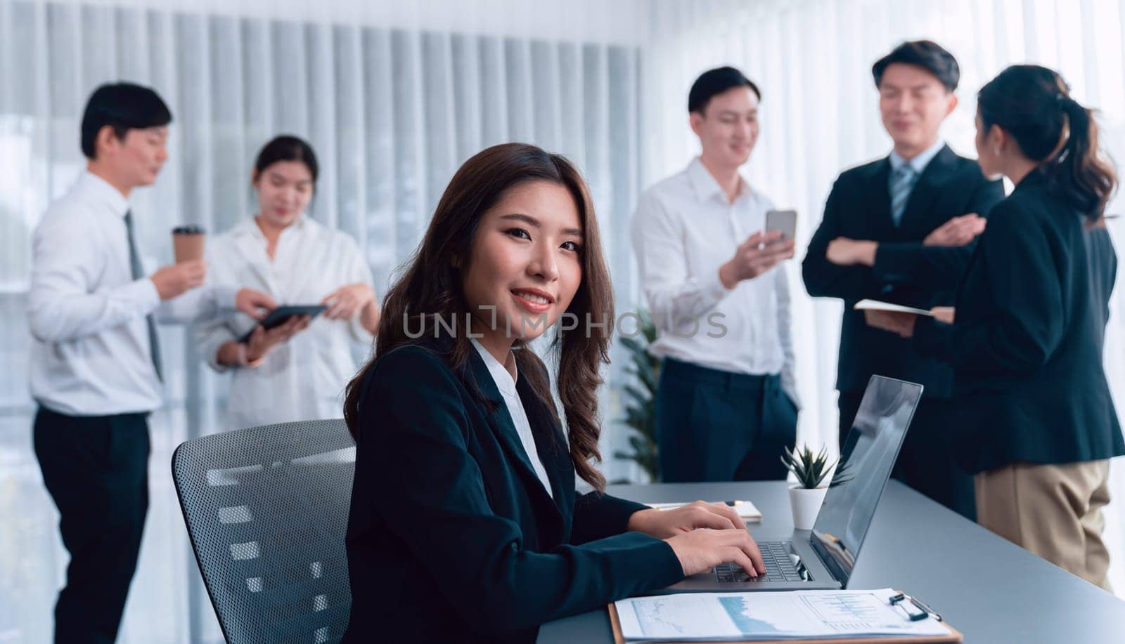 Focus portrait of female manger, businesswoman in the harmony meeting room with blurred of colleagues working together, analyzing financial paper report and dashboard data in background.