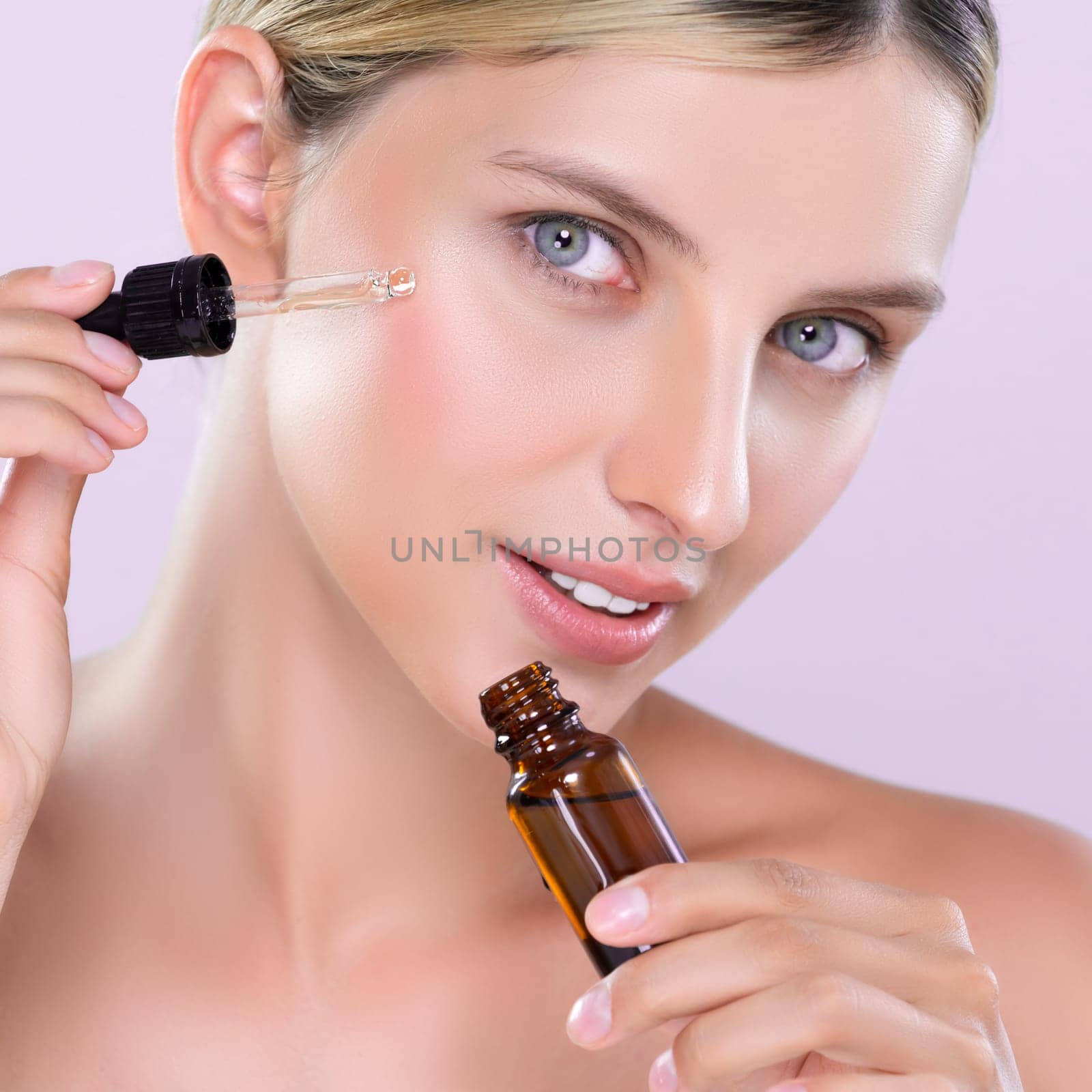 Alluring portrait of beautiful woman applying CBD oil as facial skincare concept by biancoblue
