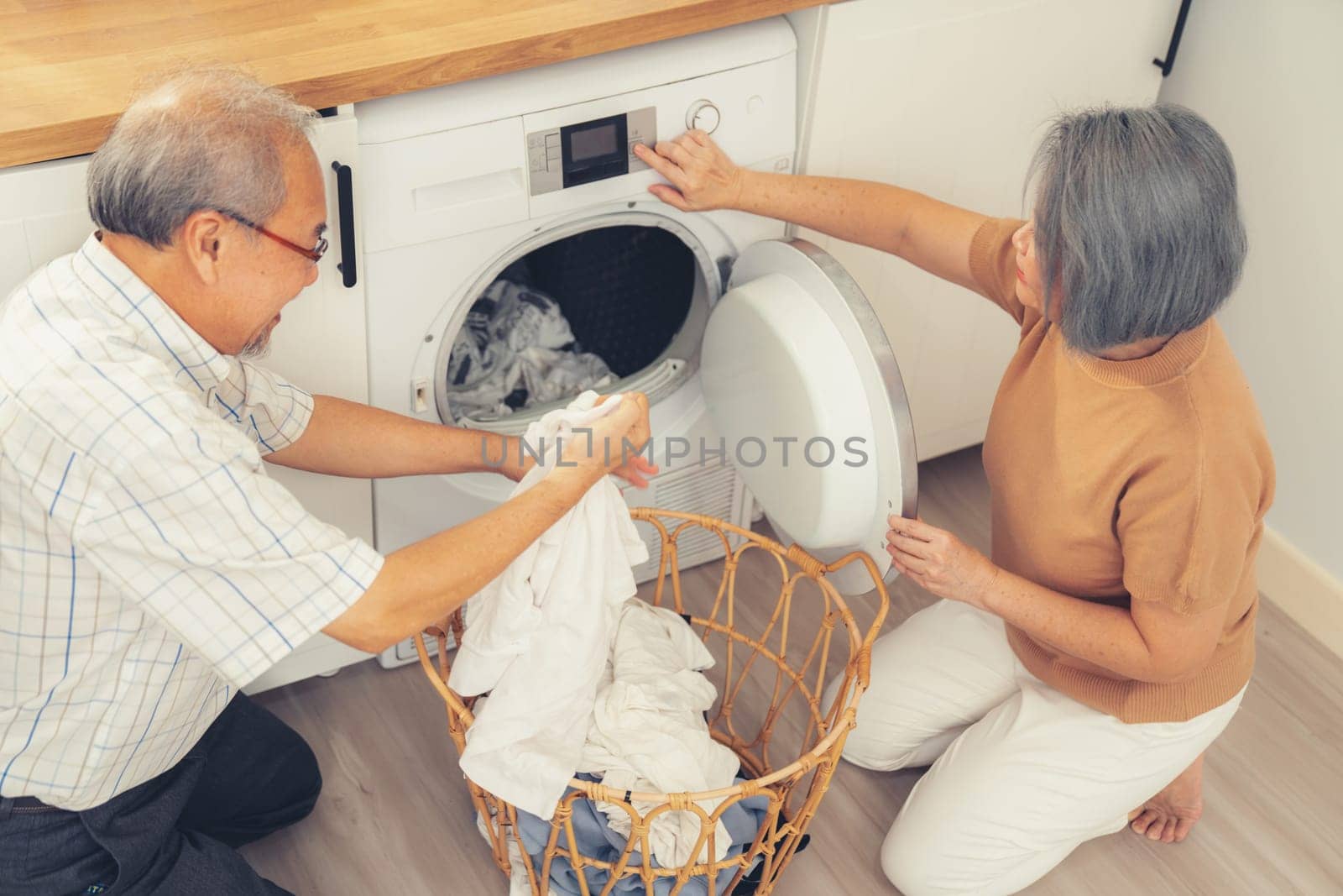 Contented senior couple doing laundry together. by biancoblue