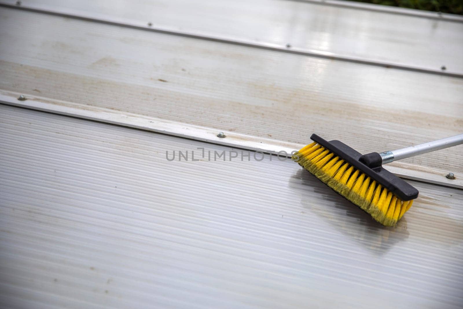 Washing the patio pergola roof cover made of aluminum. removing the dirty algae with brush soap and water close up in garden from a house terrace cleaning, workers, concept