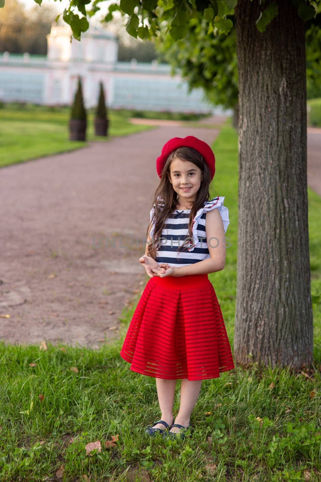 A little girl, dressed in a French style, stands in summer park by Zakharova