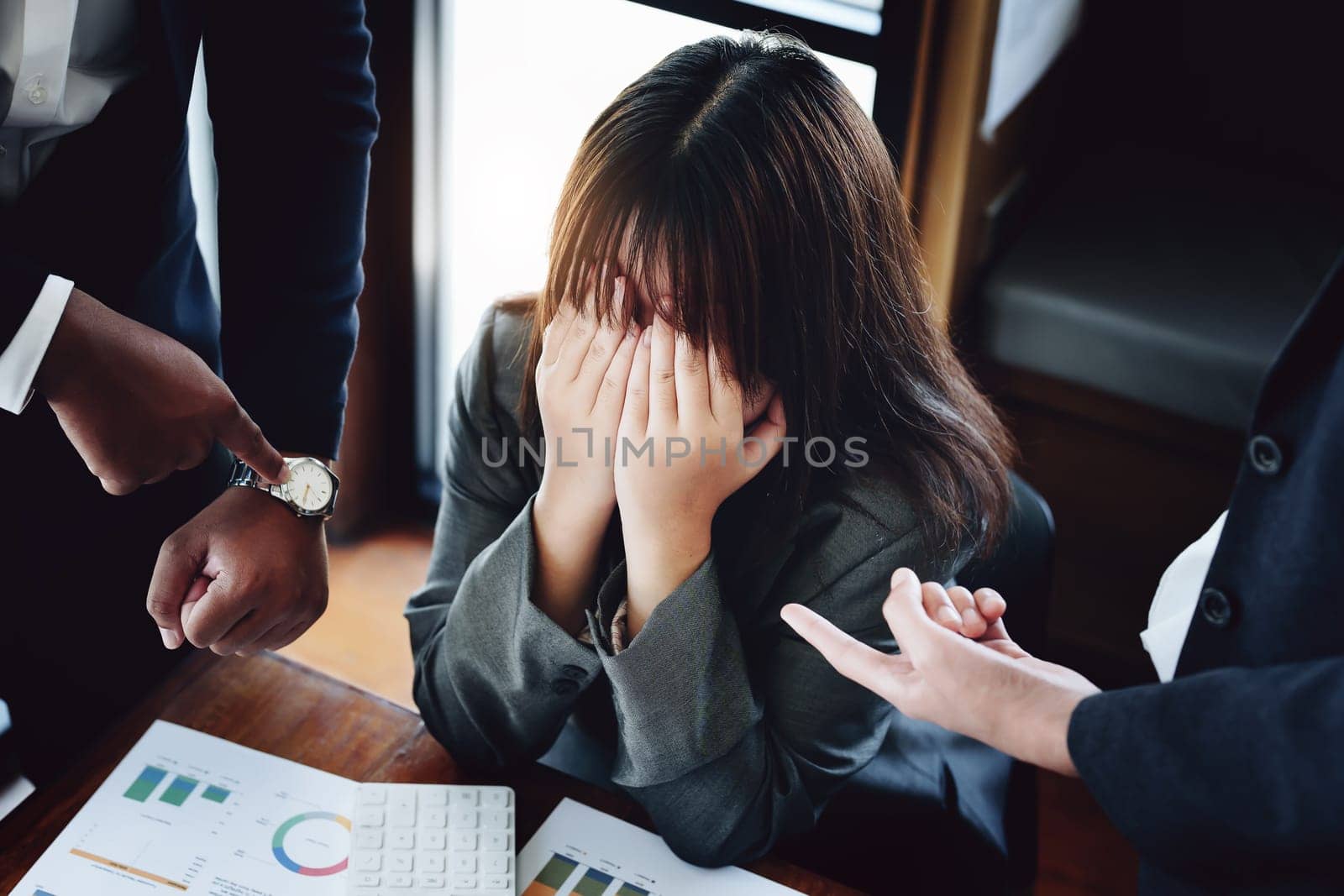 Portrait of a female worker showing failure at work and being reprimanded by a colleague.