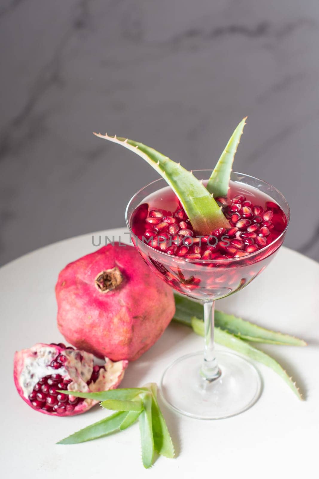 bright pomegranate juice with aloe vera, delicious alternative medicine, still life on white table. High quality photo