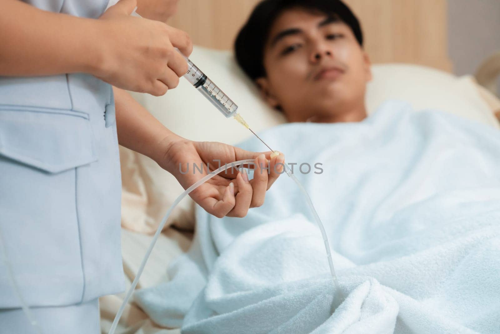 Doctor and nurse inject medicine, dosage into IV tube providing medical treatment to patient in sterile room at hospital. Fragile patient receive medical care on sick bed in recovery room.