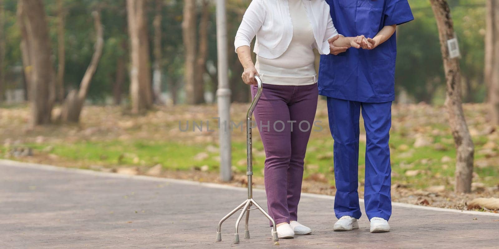 Healthcare nurse, physical therapy with elderly woman at outdoor. Nurse holding hand and help elderly woman walking.