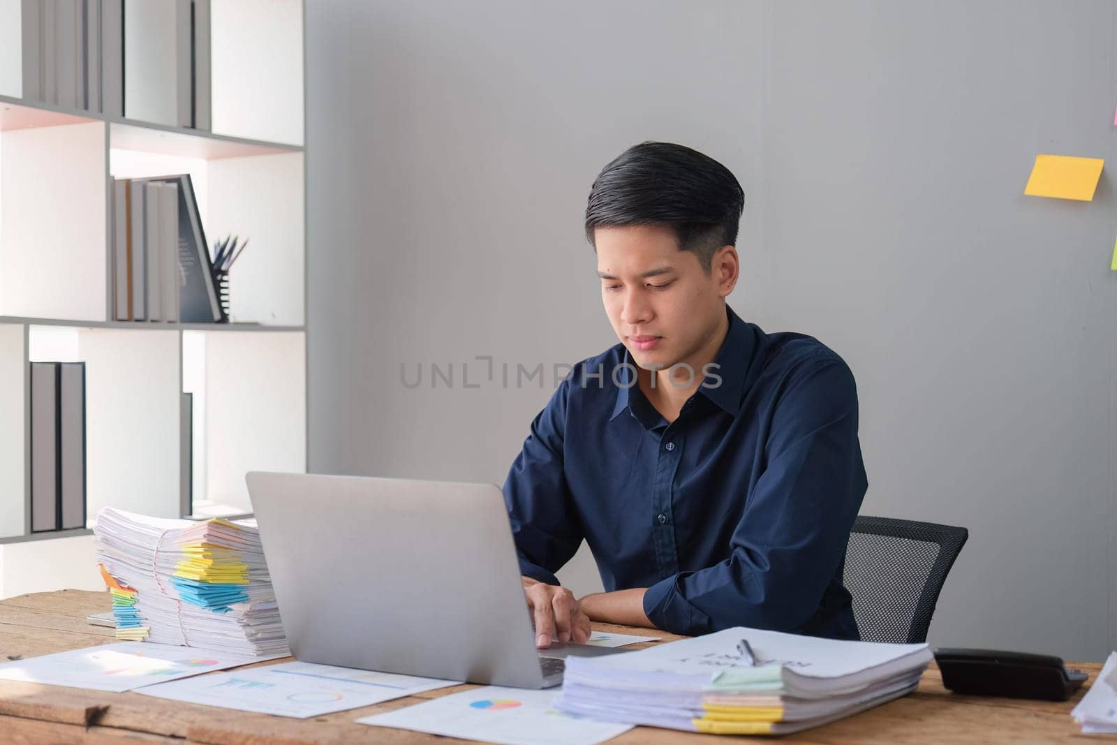 Businessman using a laptop working with documents in office.