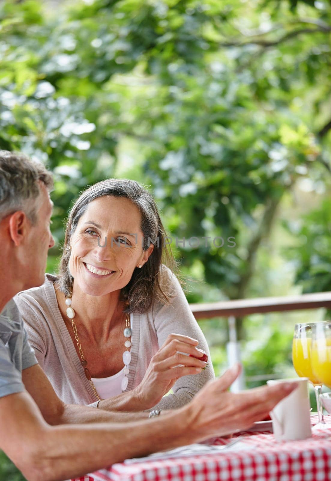 Their love grows deeper everyday. a mature couple bonding while having breakfast together outdoors. by YuriArcurs