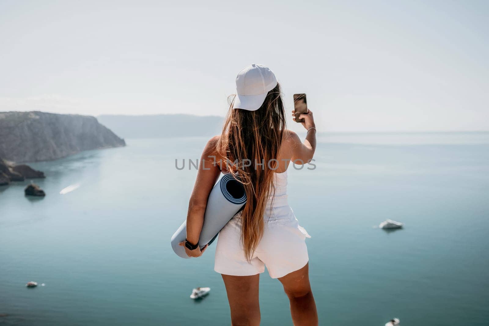 Young woman with black hair, fitness instructor in pink sports leggings and tops, doing pilates on yoga mat with magic pilates ring by the sea on the beach. Female fitness daily yoga concept
