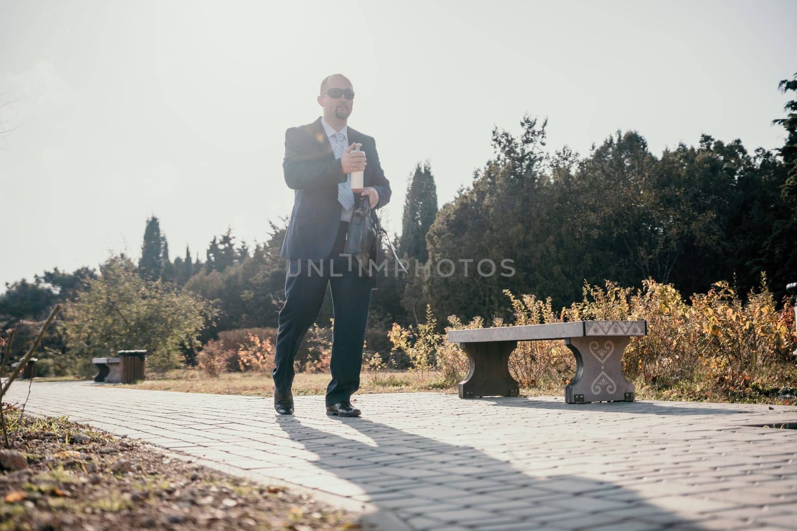 Mature entrepreneur drink coffee in autumn park. Senior executive rest in city park. by panophotograph
