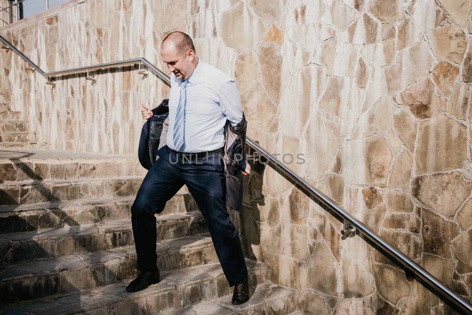 Portrait of a senior professional man in a suit with various problems. A middle-aged businessman with a briefcase descends the stairs.