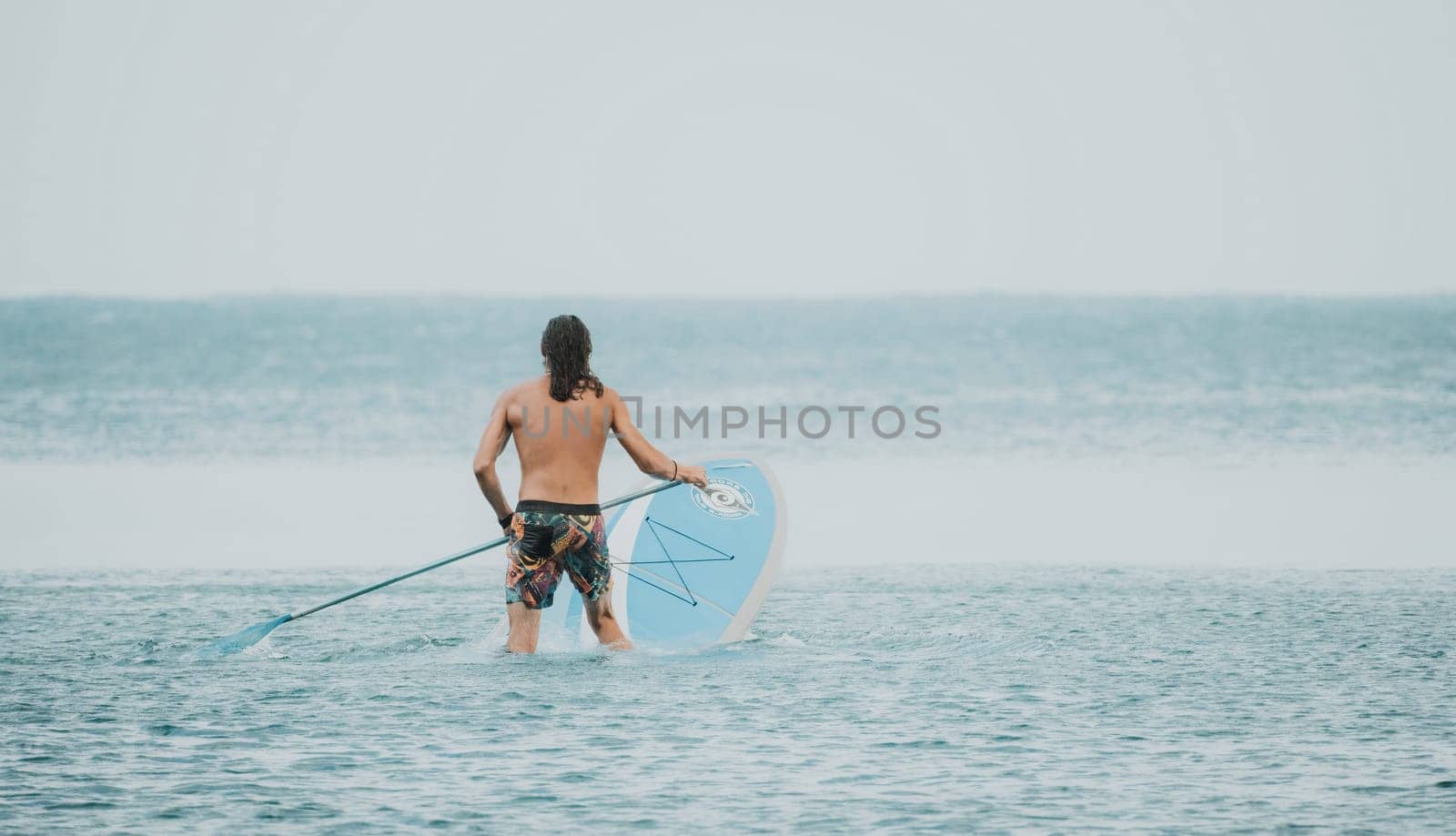 Sea woman and man on sup. Silhouette of happy young woman and man, surfing on SUP board, confident paddling through water surface. Idyllic sunset. Active lifestyle at sea or river