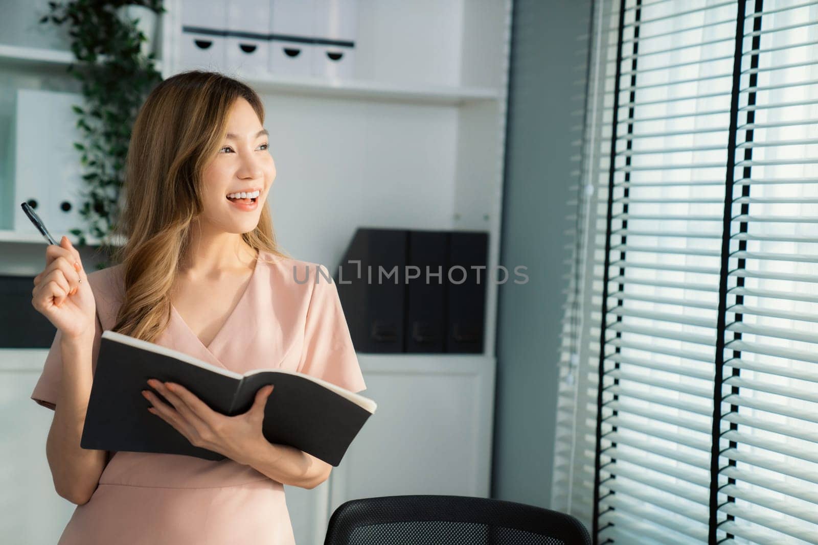 Young competent office lady, intern, secretary holding a log in office room. by biancoblue