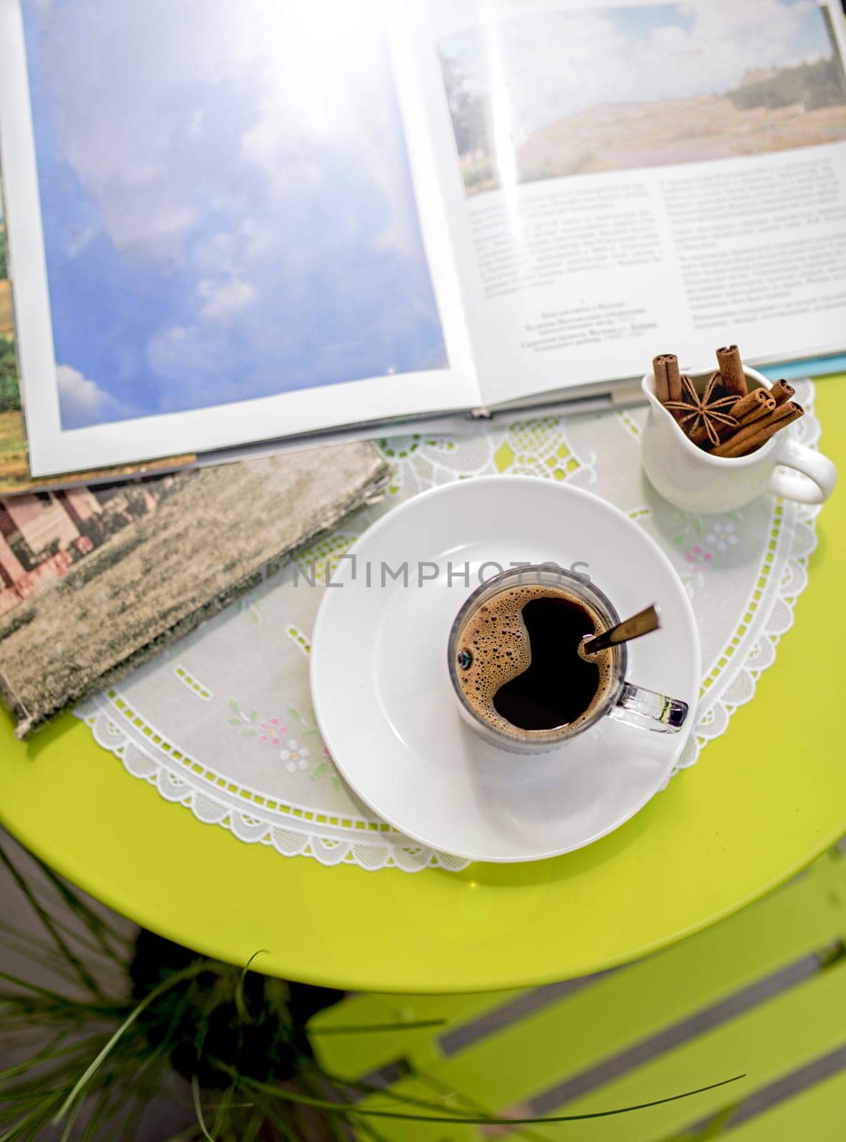 Close-up of books with photos and a cup of coffee on a table in the street by aprilphoto