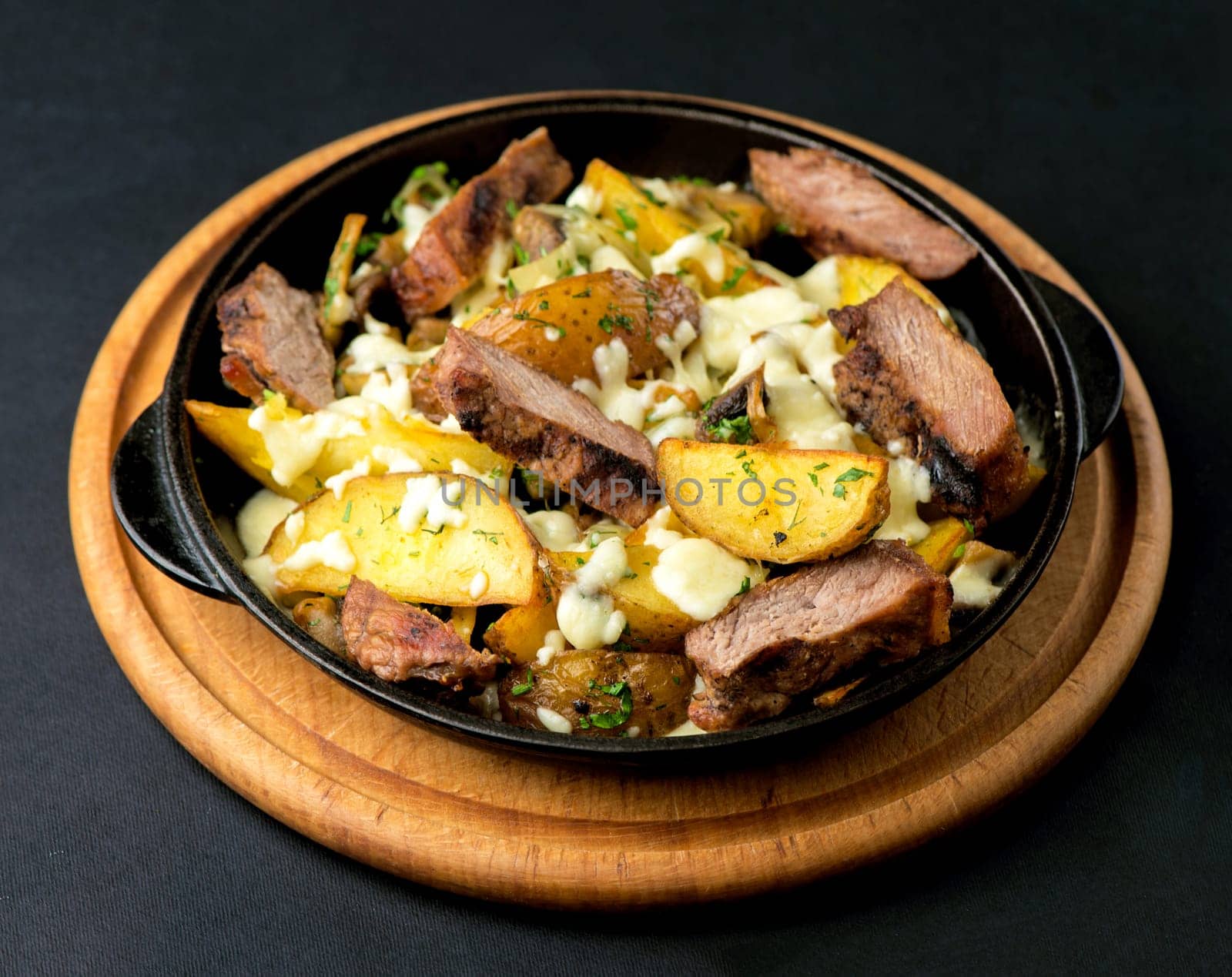 potatoes with meat and cheese baked in the oven on a dark background by aprilphoto