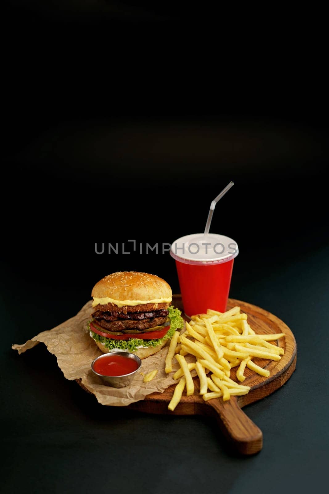 Homemade delicious double burger with beef, lettuce, bacon, tomato and cheese on a wooden background.