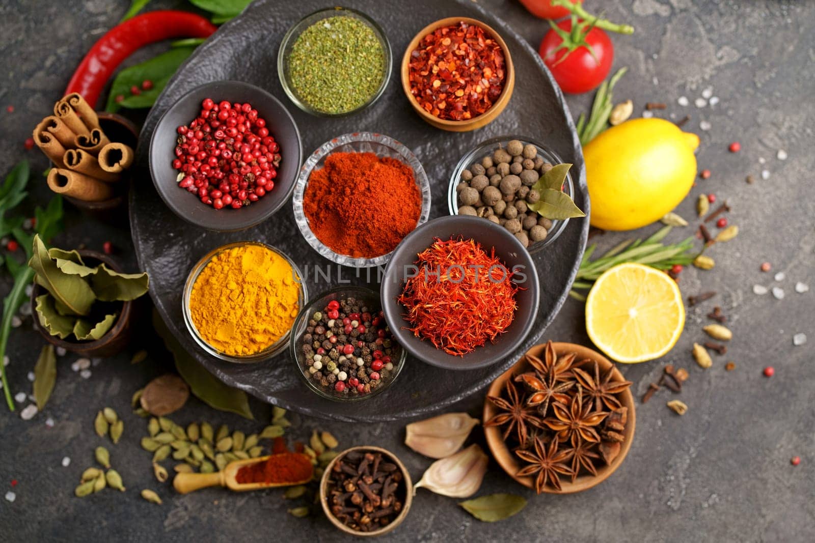 Set of spices and herbs. Indian food. Pepper, salt, paprika, basil, turmeric. On a black wooden board. View from above. Free copy space. by aprilphoto