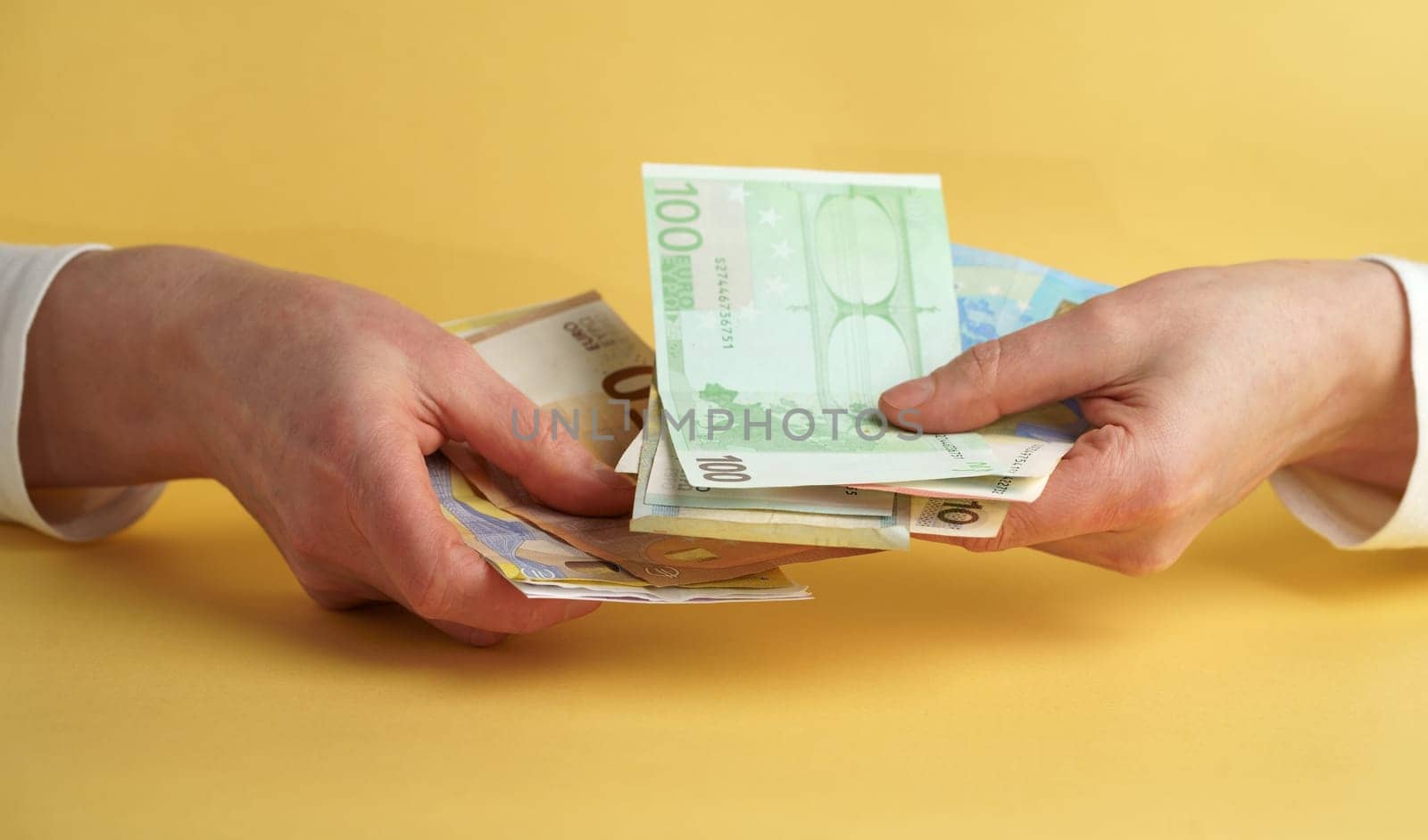 Female hands holding euro banknotes on a yellow background. Euro Money. euro cash background