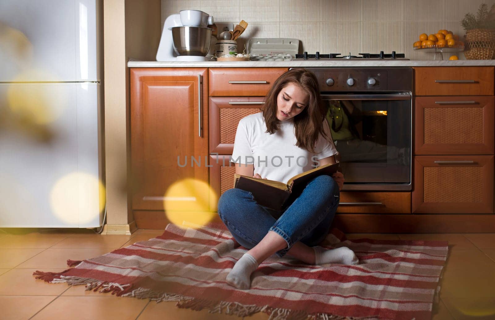 pretty young woman at home in a cozy kitchen plans to cook dinner