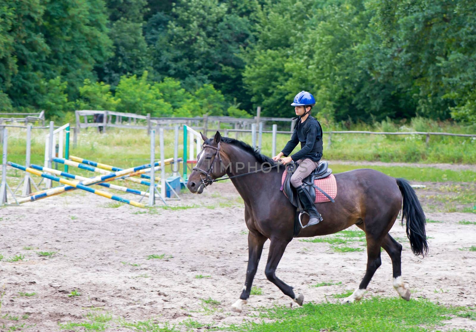 Boy and horse. Horseback Riding. Jumping. Sportsman boy on a brown horse breaks a barrier by aprilphoto
