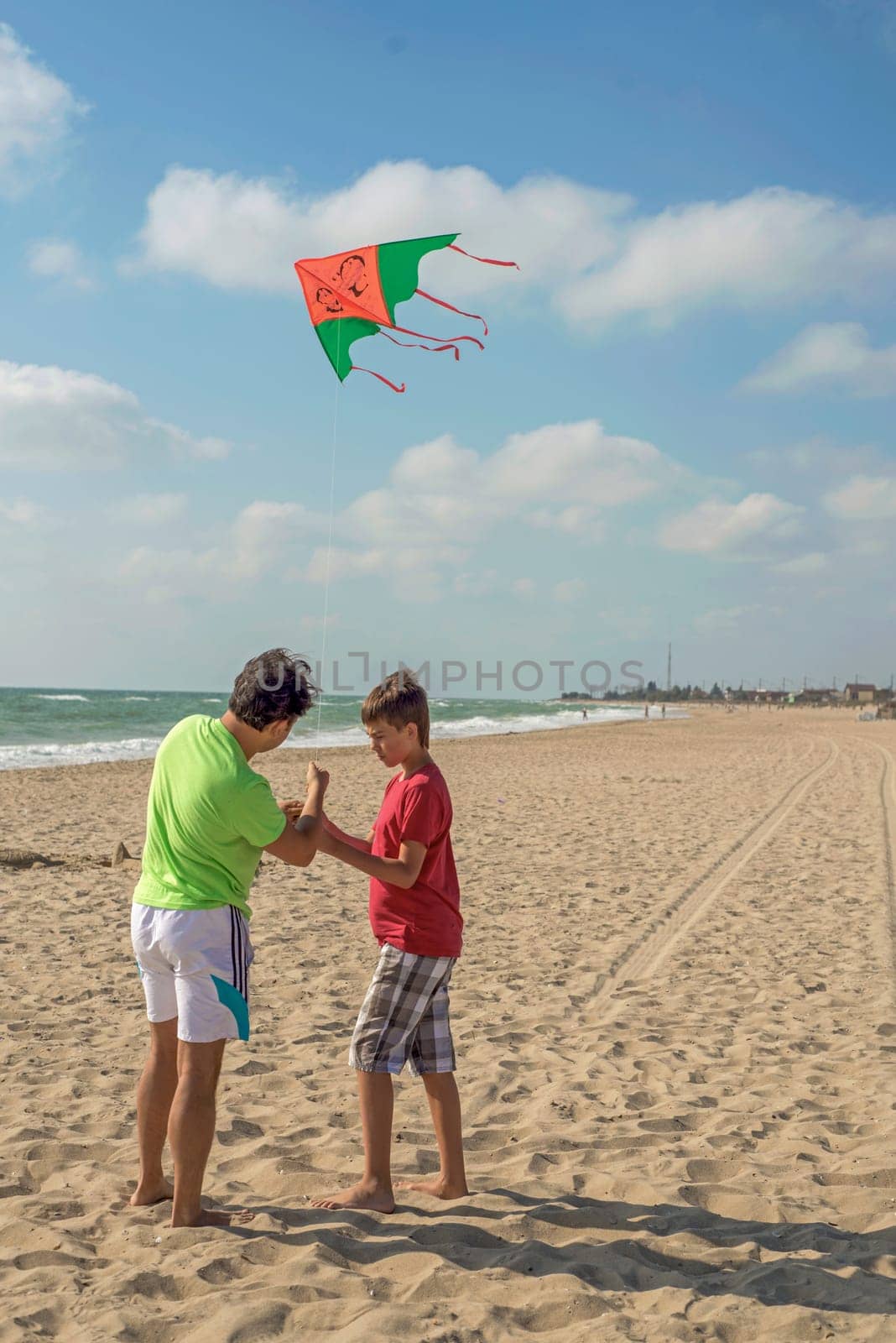 Rest of parents with children. Dad and son fly a kite near the sea
