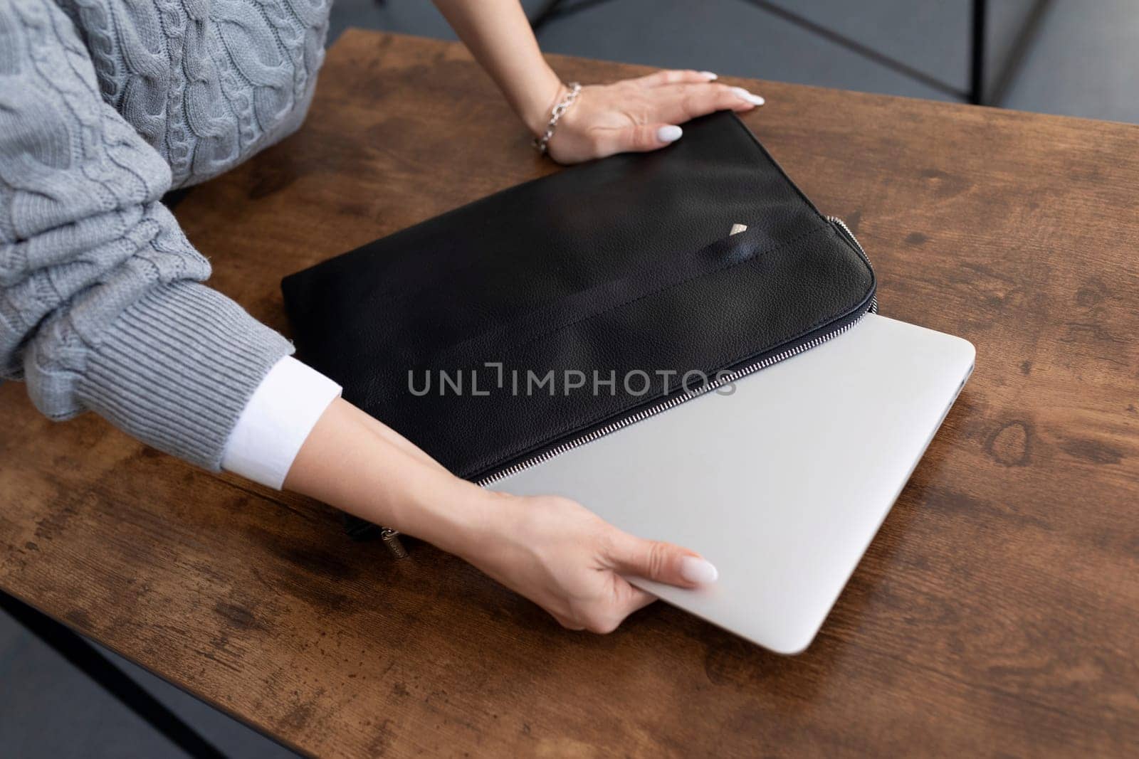 graphic designer taking out laptop from leather case in office.