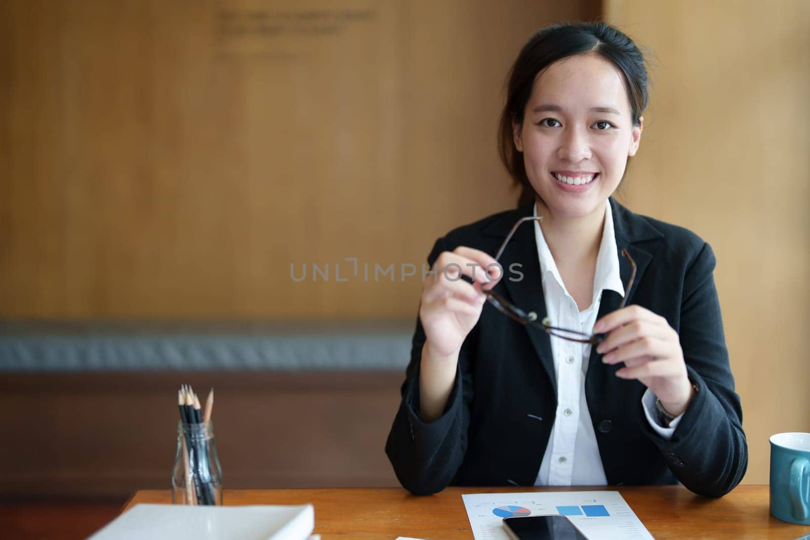 Portrait of a young Asian woman showing a smiling face using a computer and financial statements.