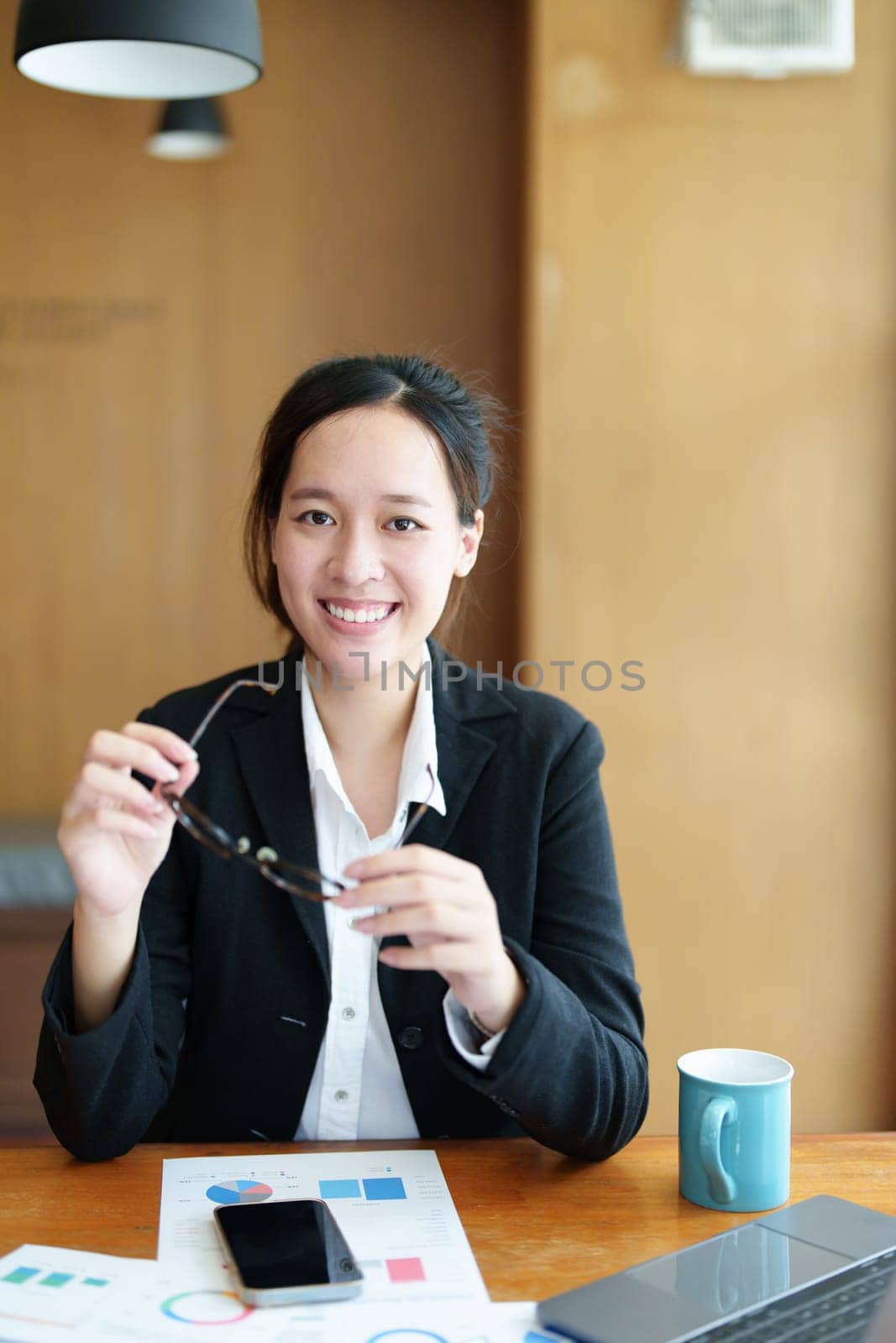 Portrait of a young Asian woman showing a smiling face using a computer and financial statements.