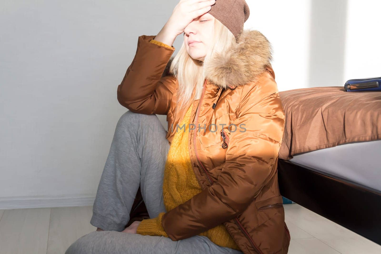 A girl in a yellow sweater and jacket holds her head with her hands from big problems and stress. The concept of the economic crisis and large utility bills in homes