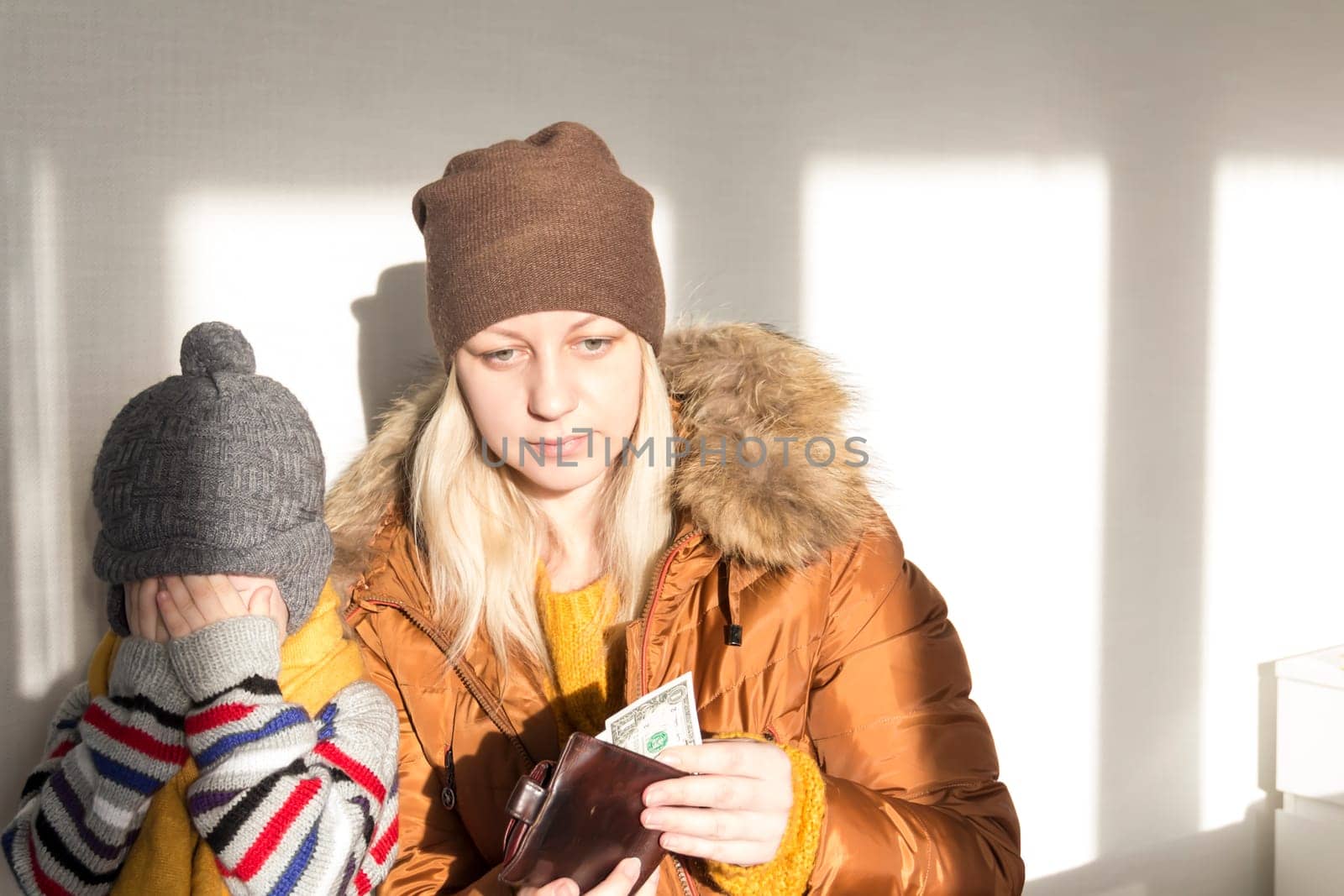 A small child is crying in her mother's arms from problems and stress. The concept of the economic crisis and large utility bills in homes