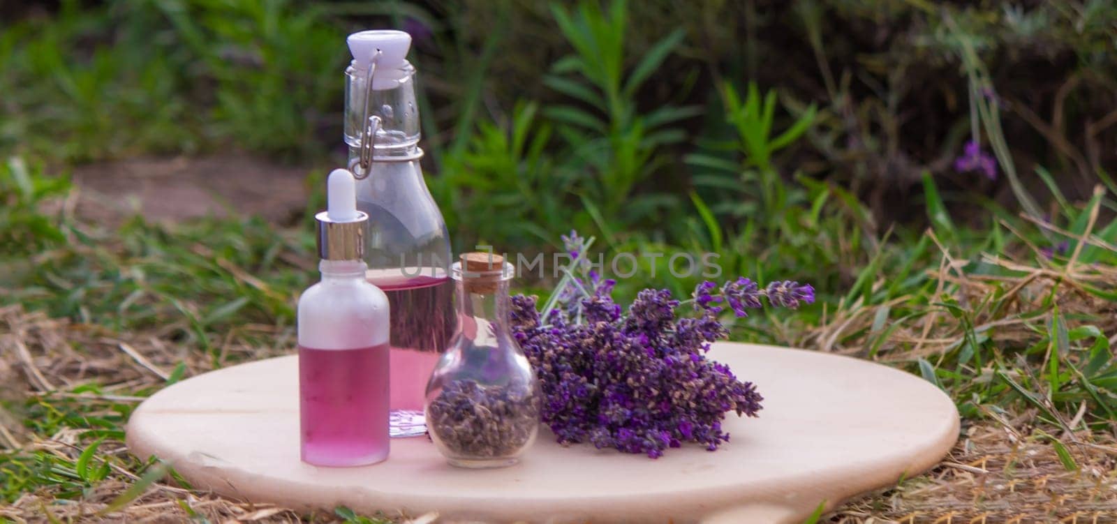 jars with lavender oil, lavender flowers, on the background of a lavender field. Selective focus