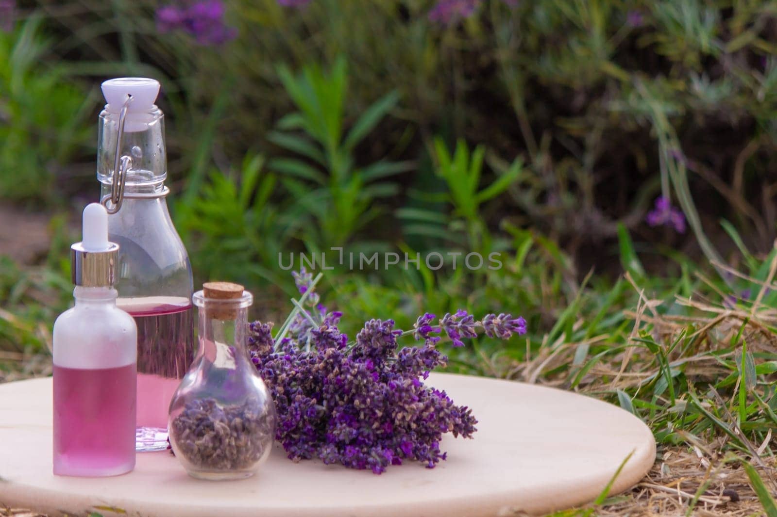 jars with lavender oil, lavender flowers, on the background of a lavender field. Selective focus