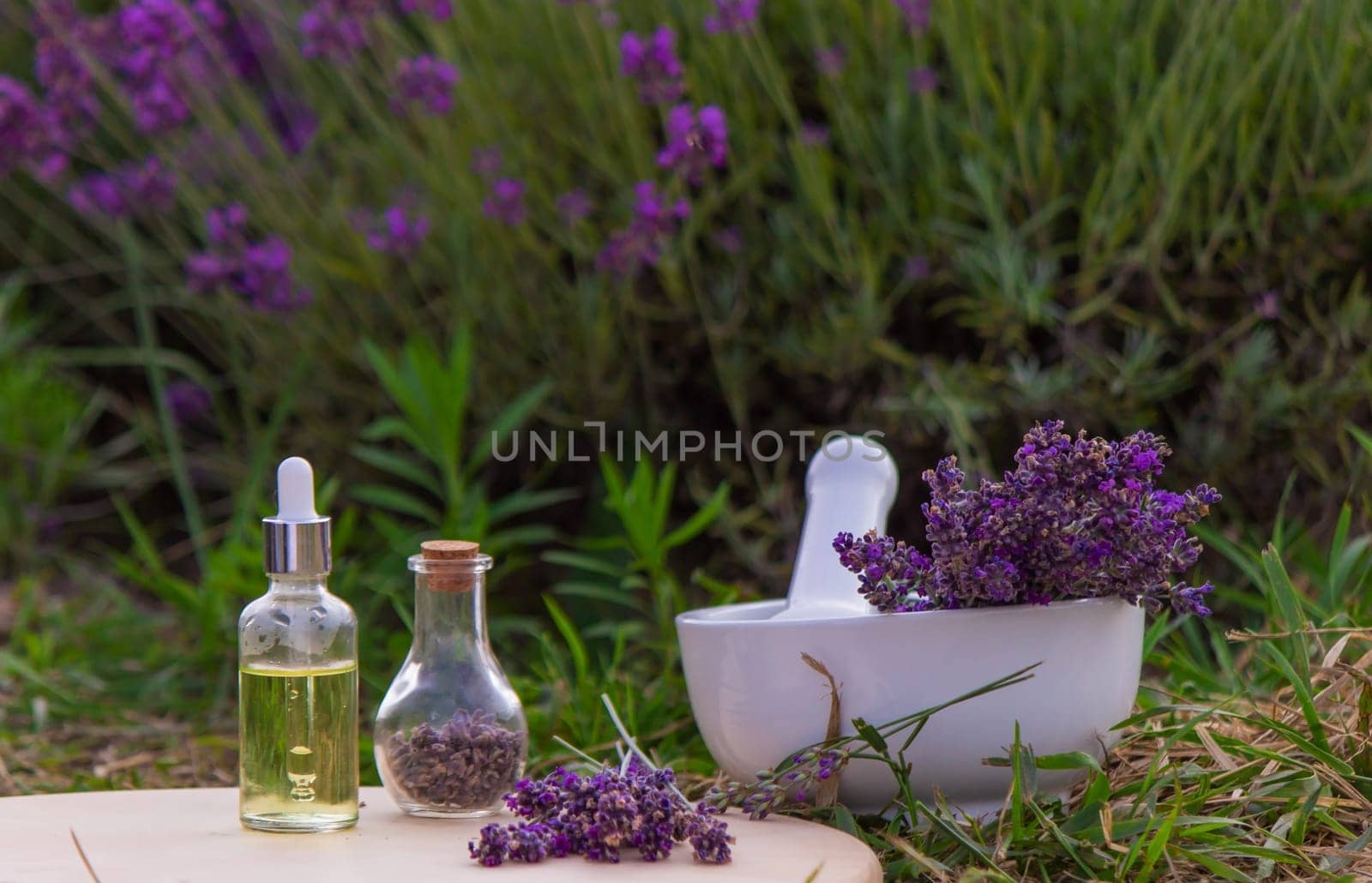 jars with lavender oil, lavender flowers, on the background of a lavender field. Selective focus