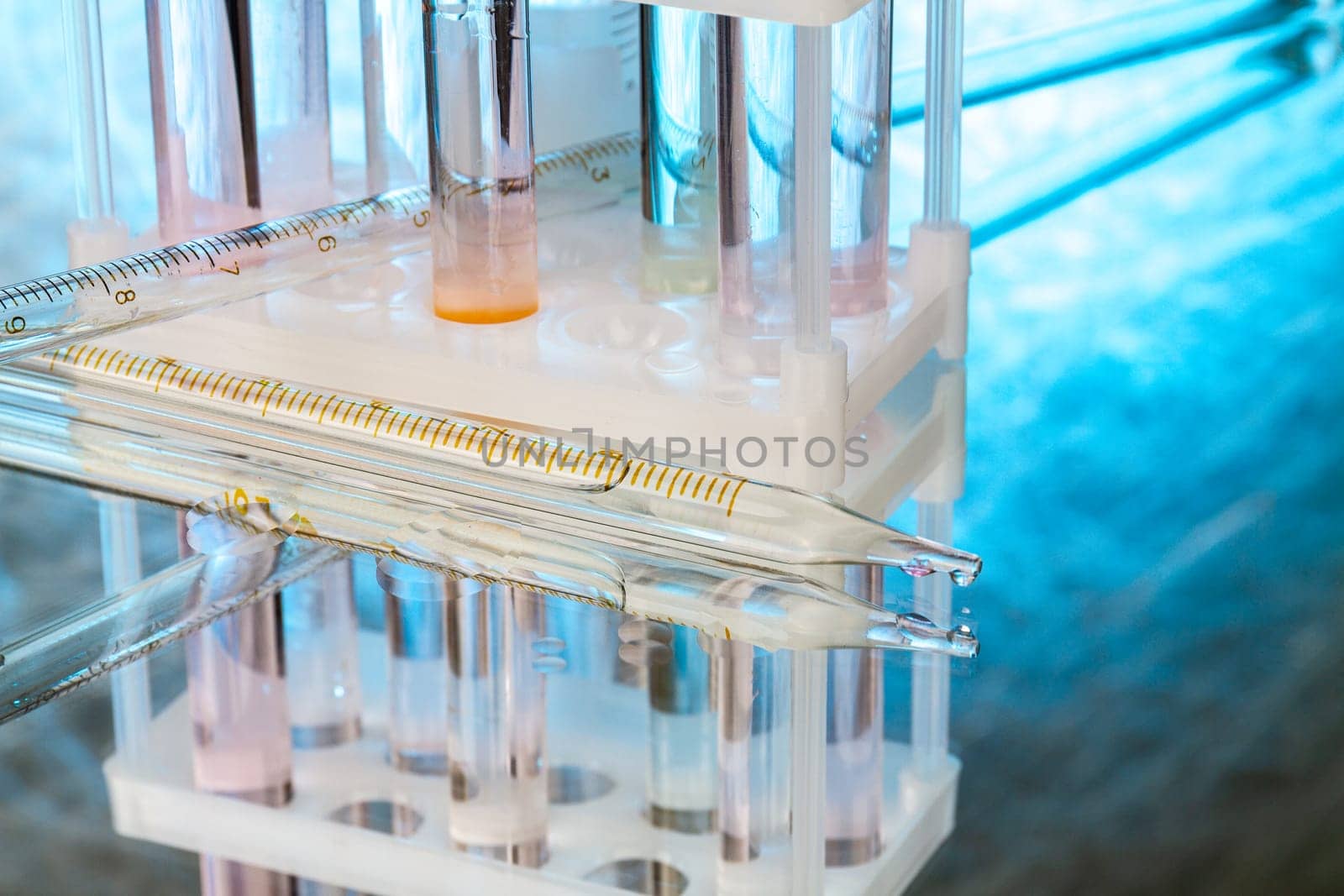 Close up laboratory glass pipette with emerging drop. Glassware for medicine research.