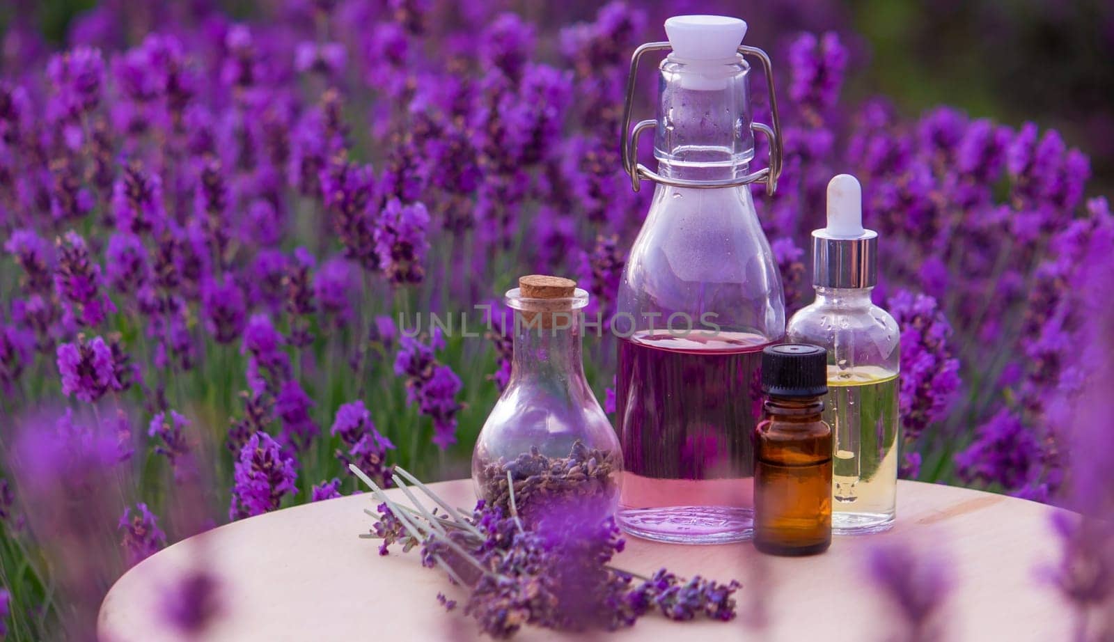 jars with lavender oil, lavender flowers, on the background of a lavender field. Selective focus