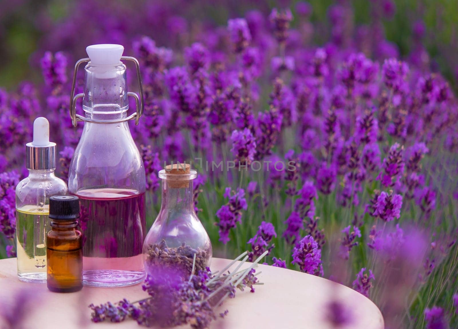 jars with lavender oil, lavender flowers, on the background of a lavender field. Selective focus