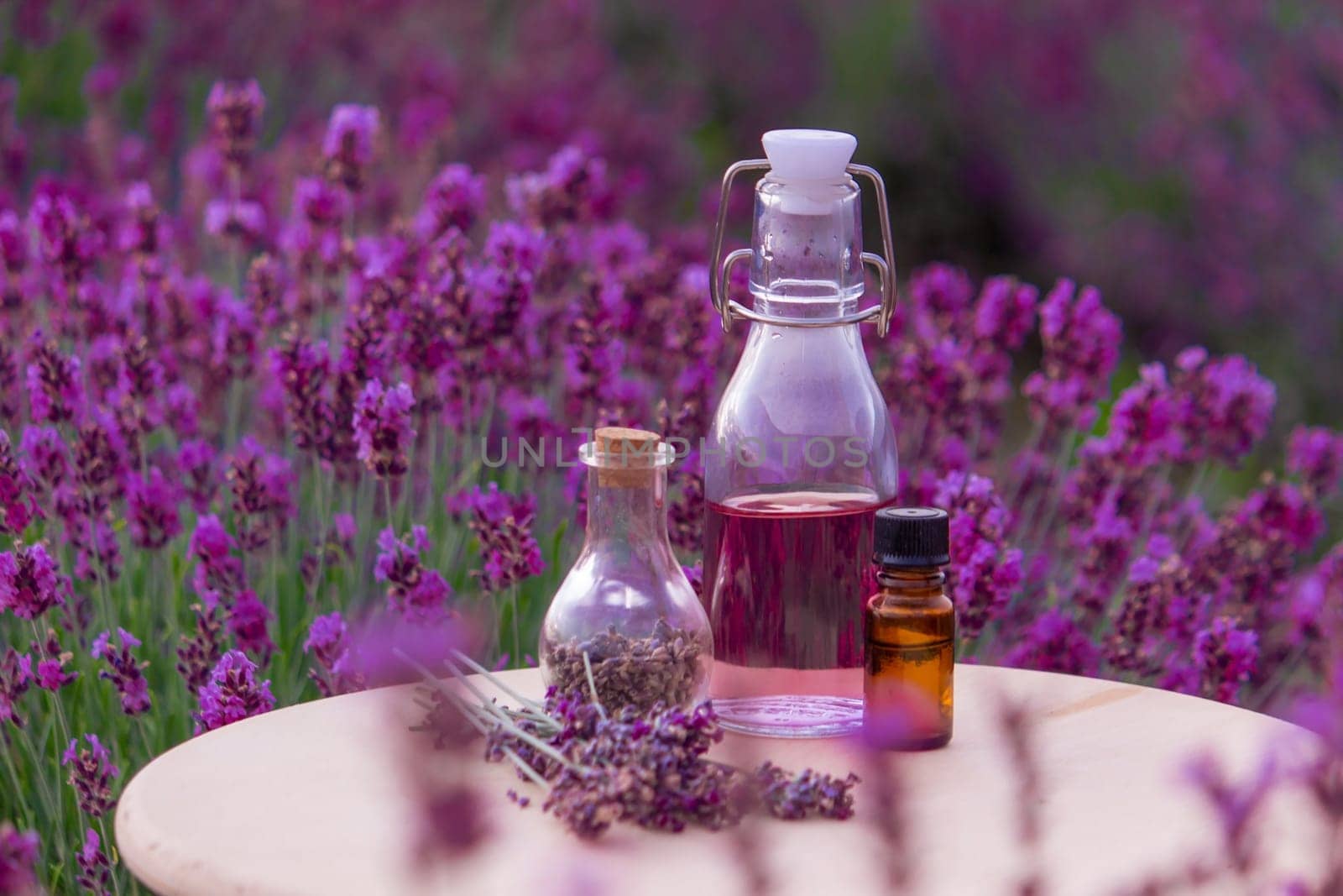 jars with lavender oil, lavender flowers, on the background of a lavender field. Selective focus