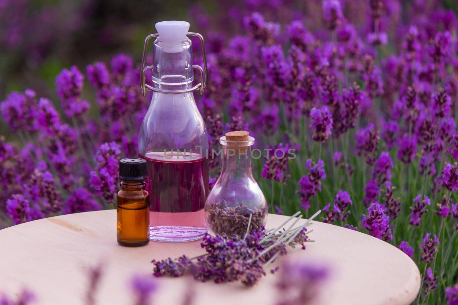 jars with lavender oil, lavender flowers, on the background of a lavender field. Selective focus